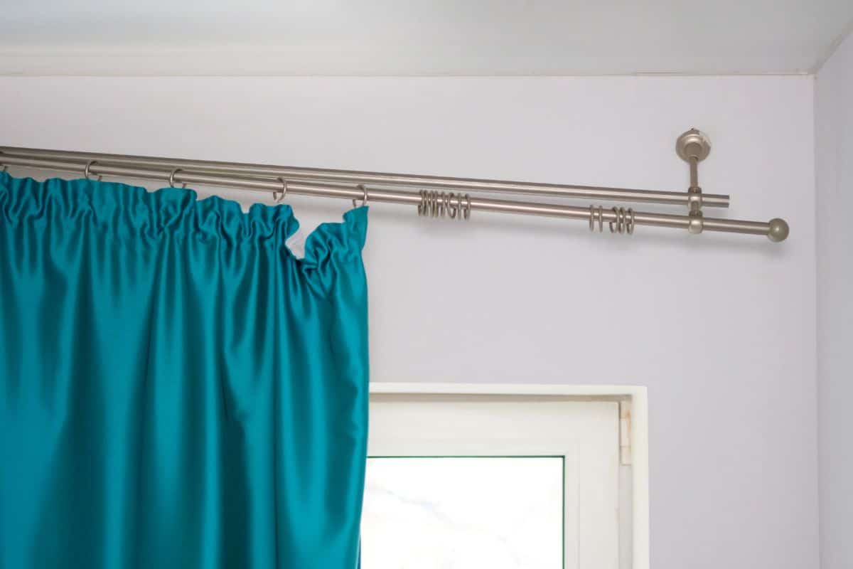 The cornice attached to the wall squinted down. The wall mount on which the curtains are hanging falls. Window and broken curtain rod with closeup. 