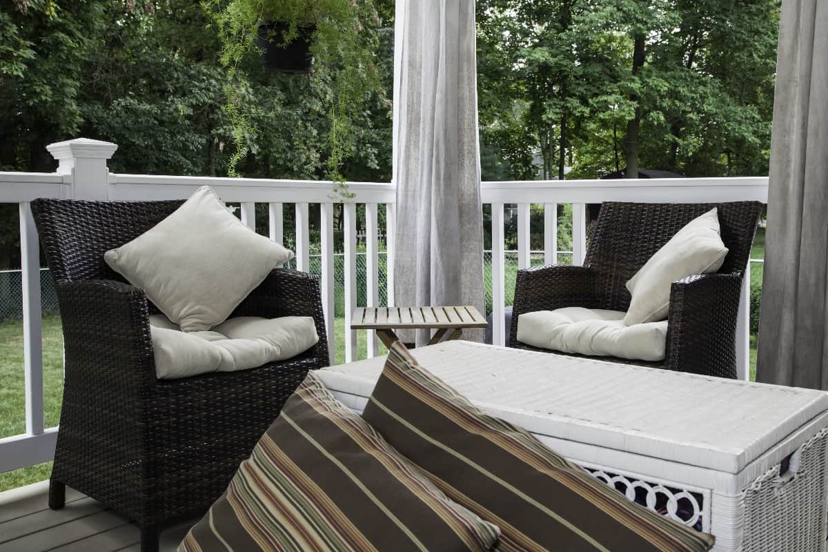 Use Magnets - Two resin wicker chairs sit on a covered deck; they have cream colored cushions and pillows;