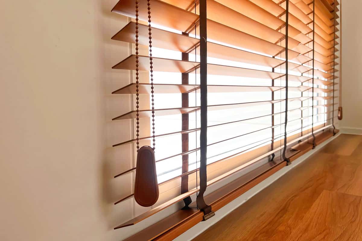 close up photo of a brown colored blinds half open on the window