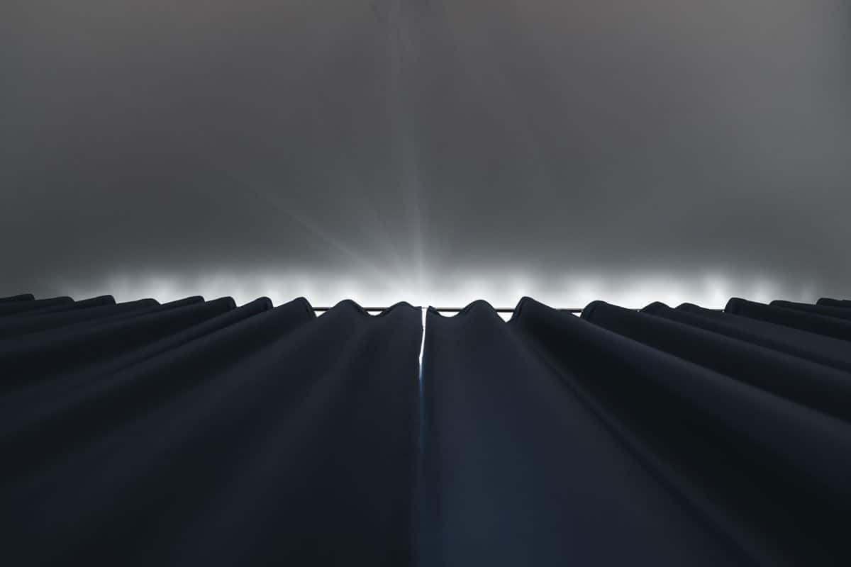 photo of a black colored black out curtain installed on a huge wide window of a bed room