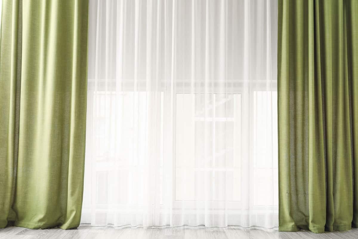 photo of a green curtain with sheers on a huge wide open window on the room inside the hotel