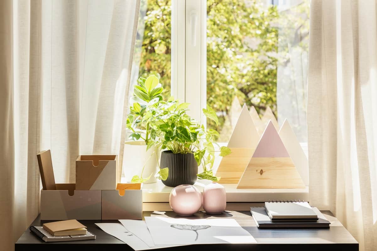 A Space To Study - Plant and triangles on window sill in bright workspace interior with posters on desk.