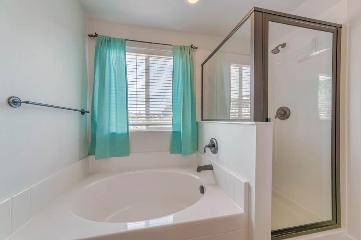 A minimalistic bathroom interior design in white color with a bathtub and shower cabin
