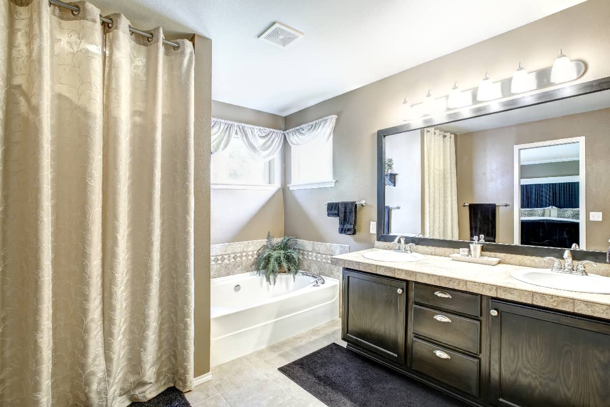 Bathroom interior in light grey tones with black vanity cabinet with large mirror
