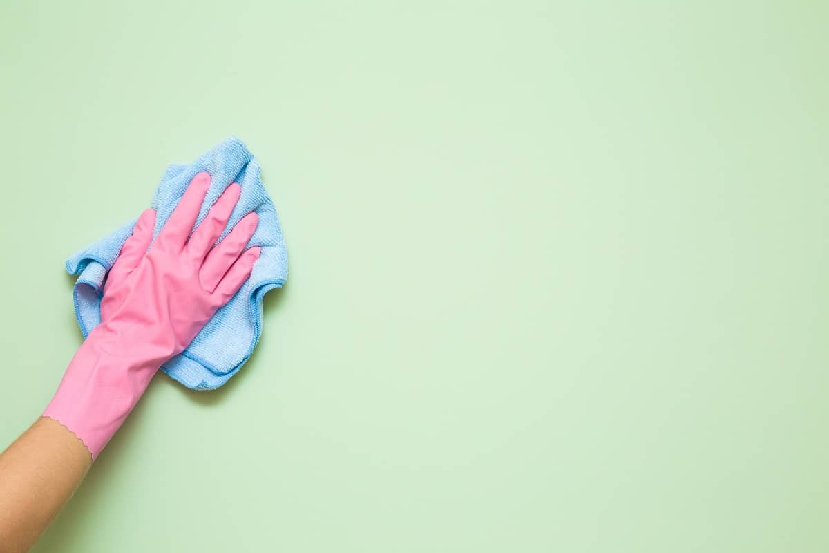Clean the Walls - hand in rubber protective glove with micro fiber cloth wiping wall from dust
