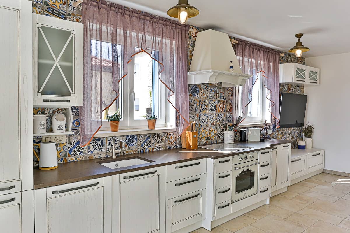 Go For a Burlap Curtain - Spacious kitchen with white cabinets and colorful tiles classic contemporary style