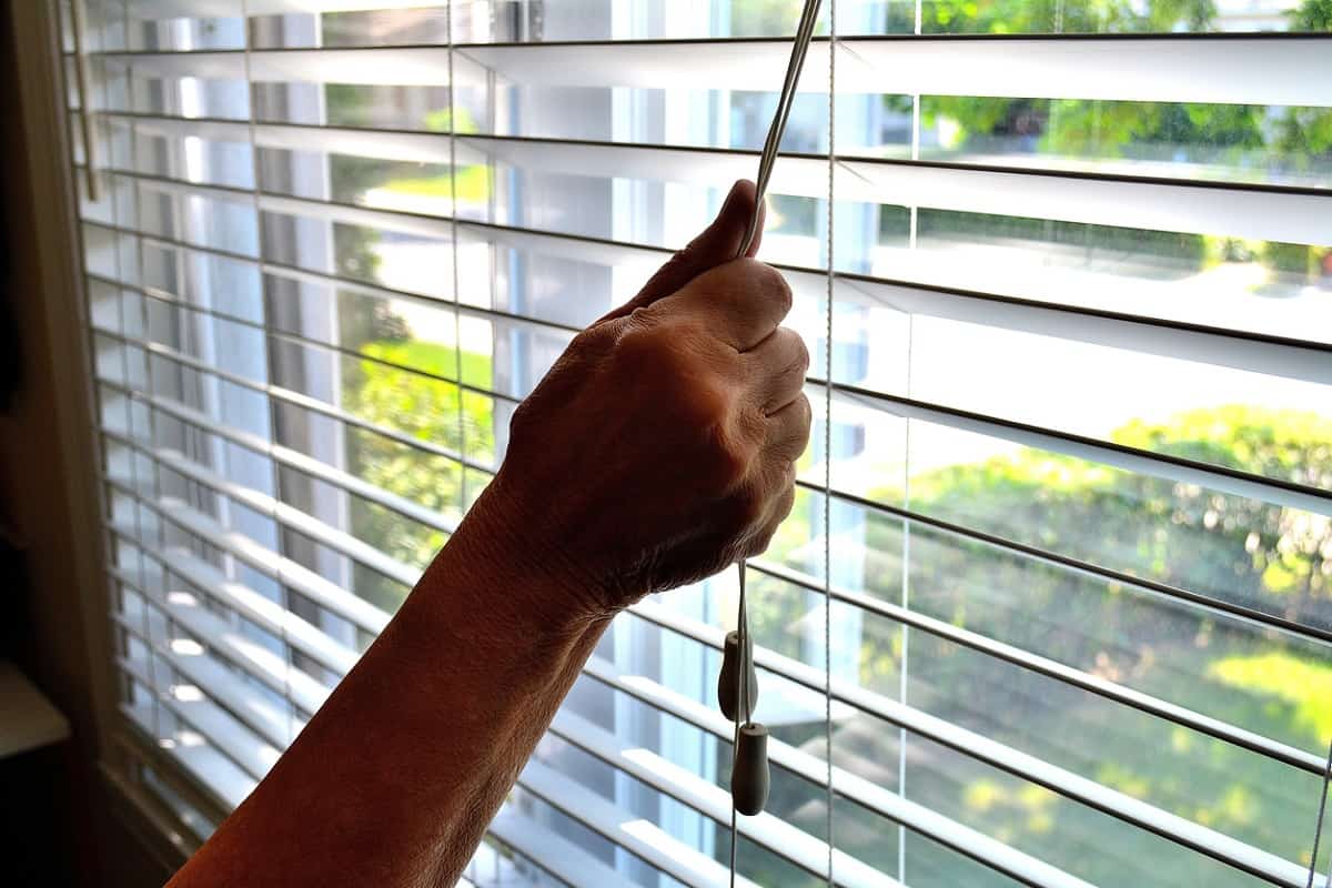 How Do Roller Blinds Work Lifestyle...This close up shot, shows an arm lowering or opening a bedroom window shade.