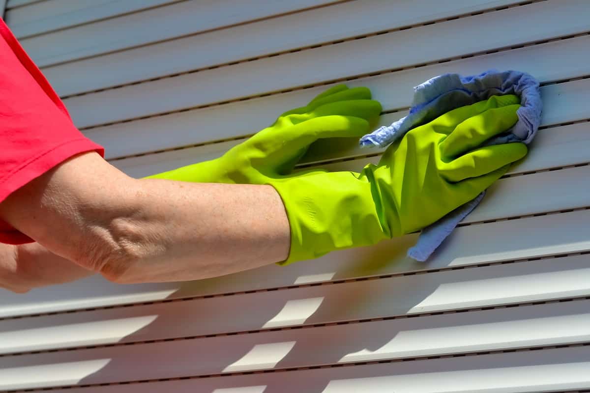 How Often Should You Clean Your Shutters - Hands of a woman cleaning shutters.