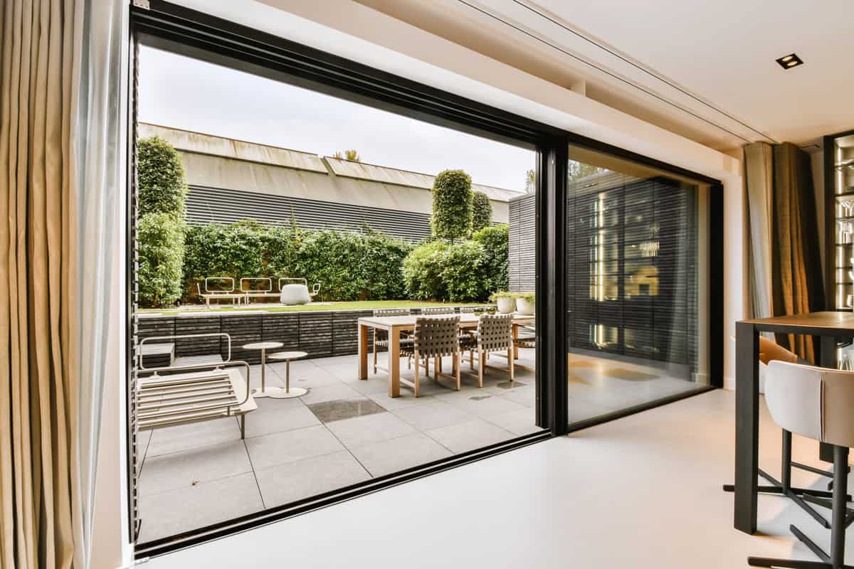 Luxurious backyard dining area with a huge sliding door covered with a ceiling high curtain