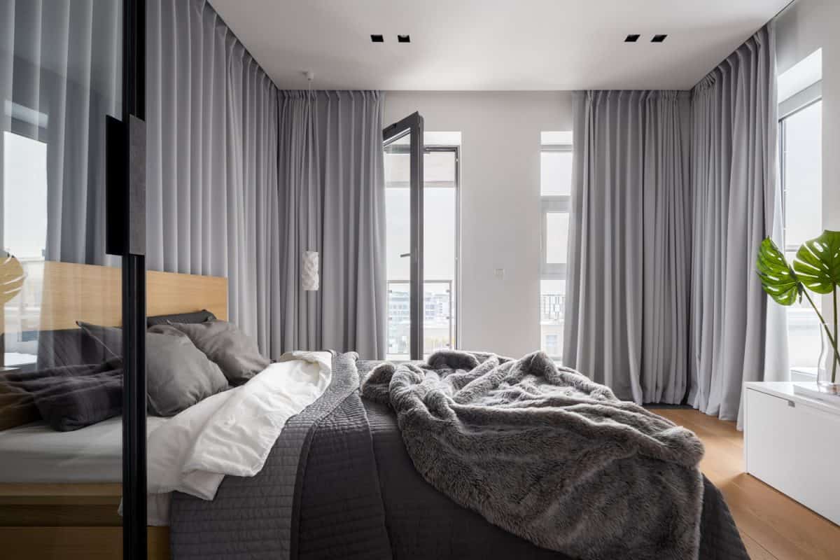Luxury bedroom interior with double bed and gray window curtains

