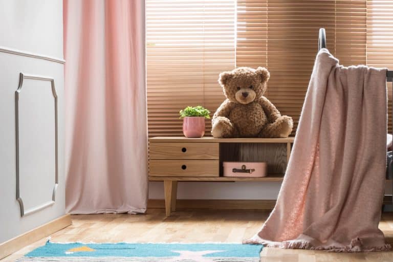 Panorama of a cozy, gray nursery bedroom interior with a classic wooden baby crib and pastel pink decorations, Curtains Or Blinds For Bedroom - Which Is Right For You?