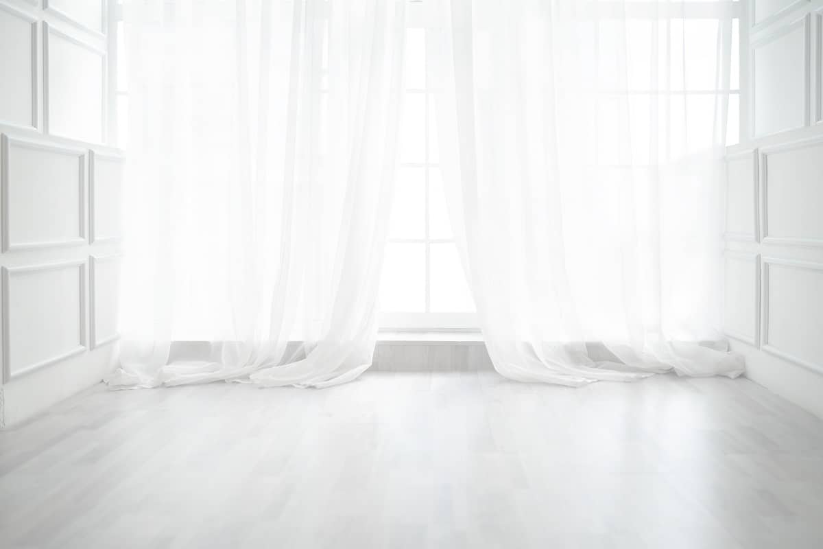 Puddled - Backlit window with white curtains in empty room