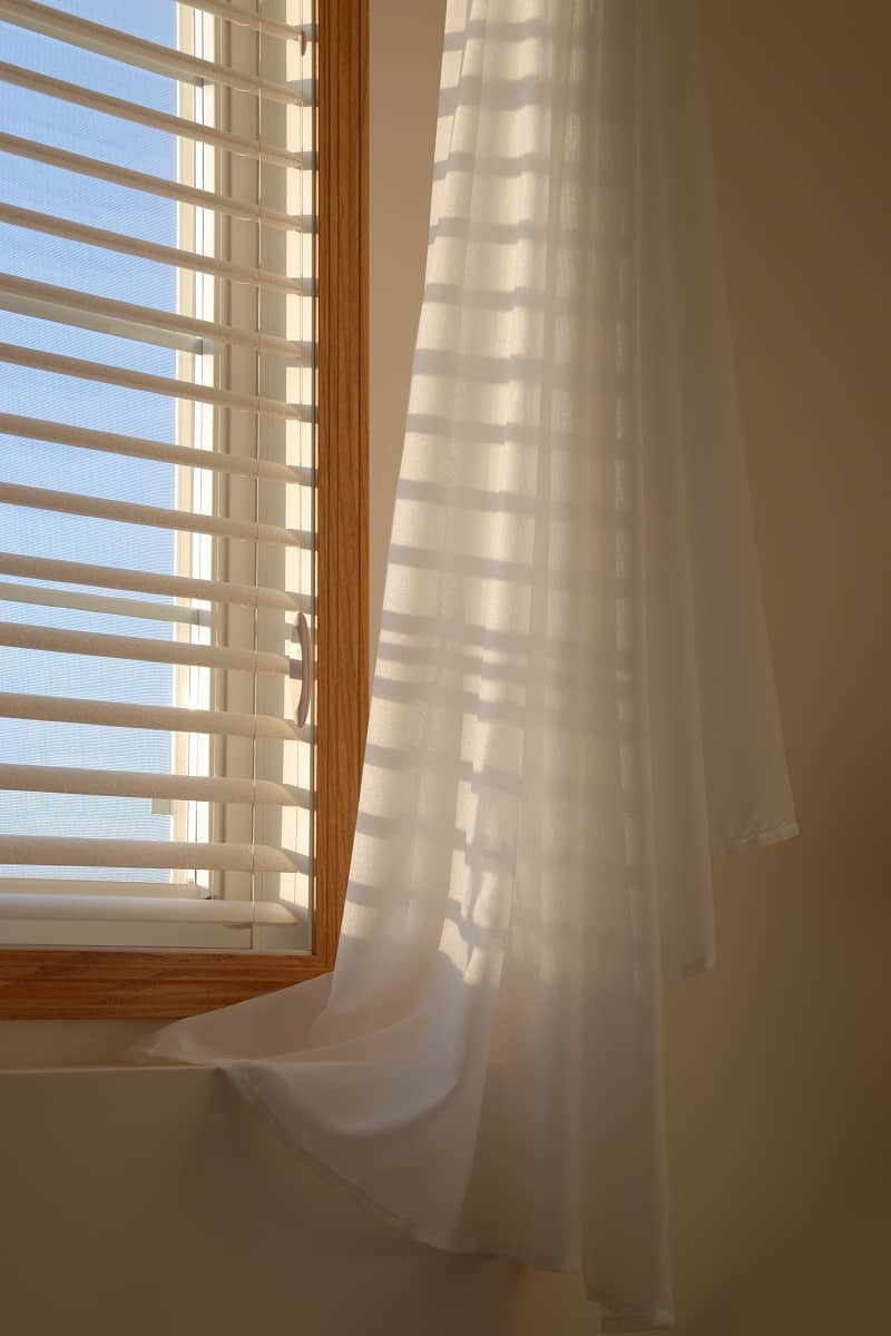 Sheers And Blinds - Shadows of the evening sun coming through window blinds leaves a soft shadow on draped sheer linen curtains