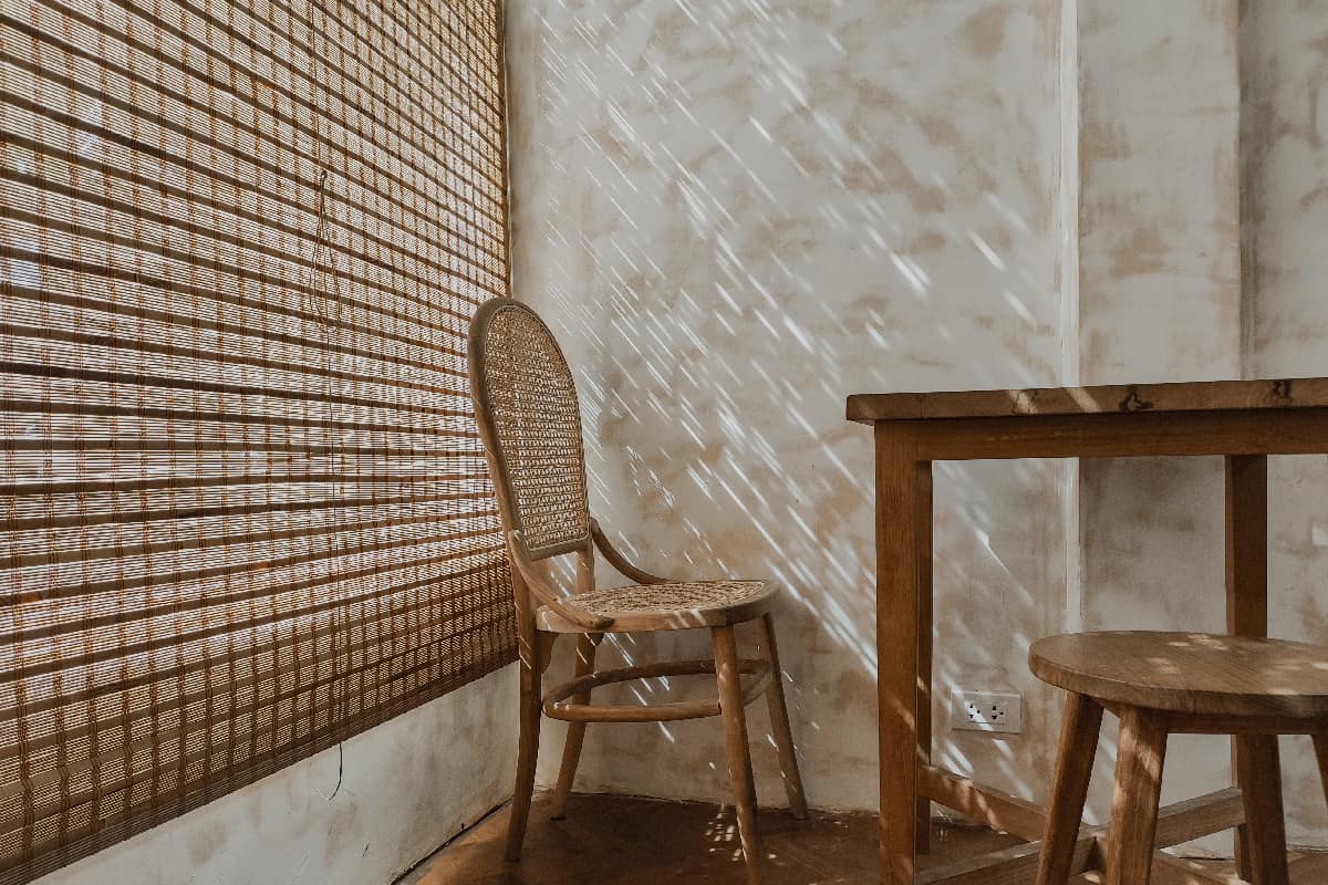 The wooden table and chairs near the window in cafe with sunlight through the bamboo window blind sunshade