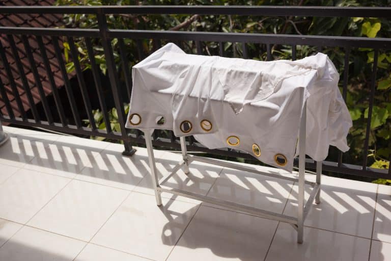 A washed curtain hanging on a dryer rack under sun, Do Curtains Shrink When Washed?