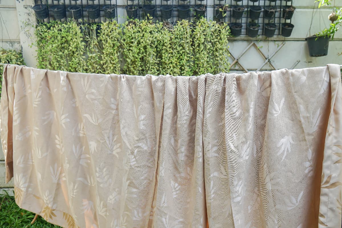 Wet beige curtain hang on the clothes line to dry in the sun