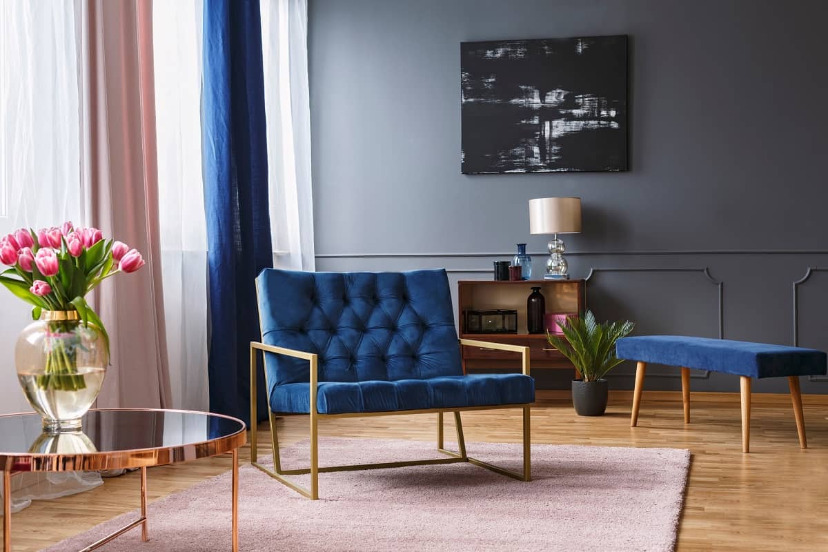 What Should Your Curtains Match - a blue, wide chair standing on a rug in a spacious living room interior