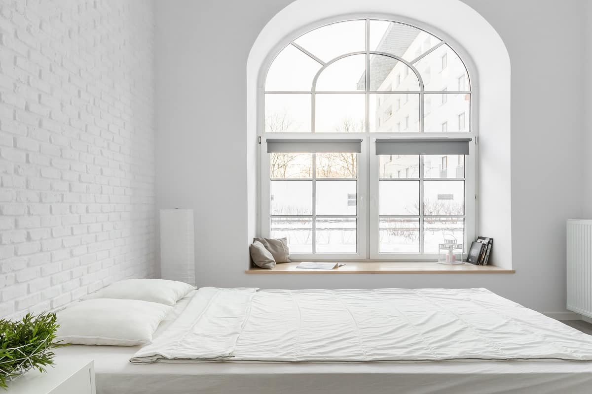 What are half circle windows- Bed from pallets in loft bedroom with white brick wall and big arch window