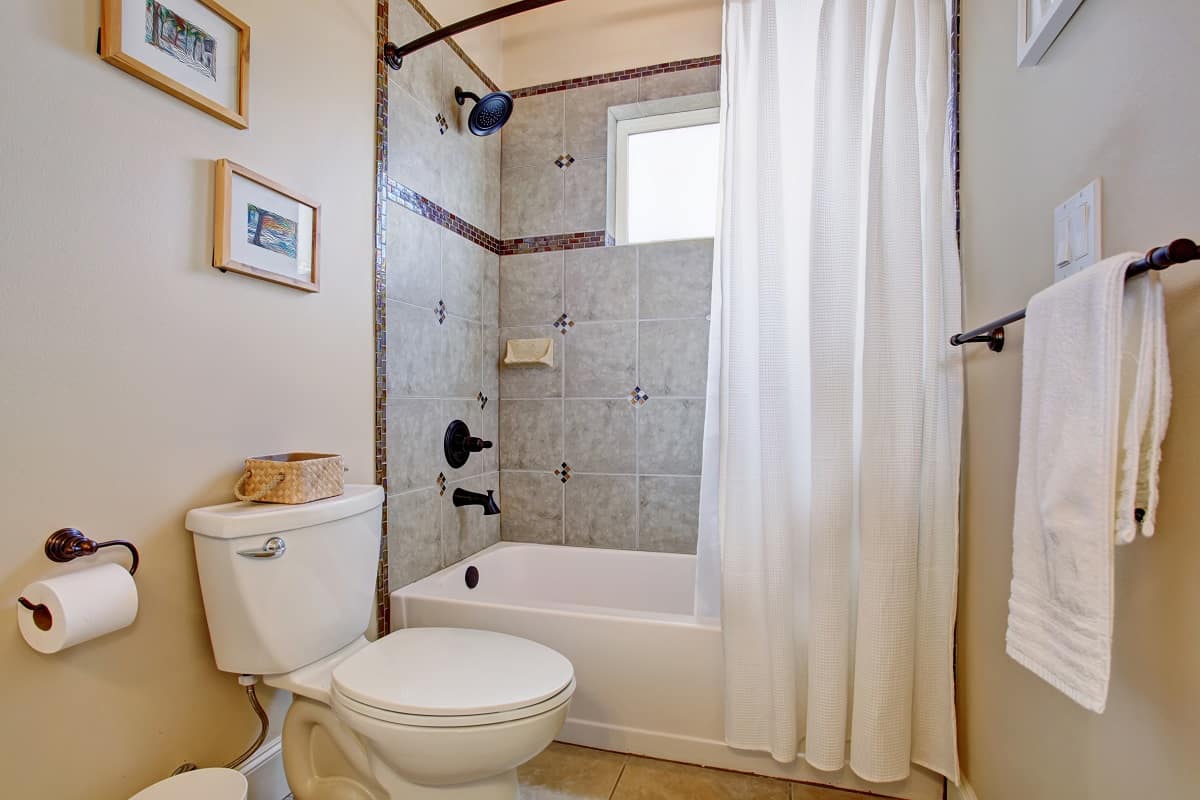 What are the advantages of shower curtains - bright bathroom with tile floor and white shower curtain.