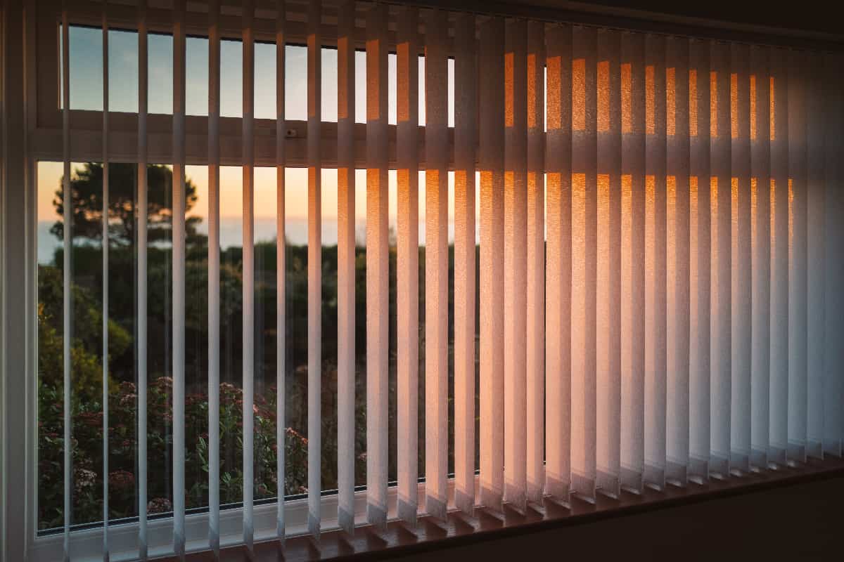 White vertical slat blinds hanging in front of a window