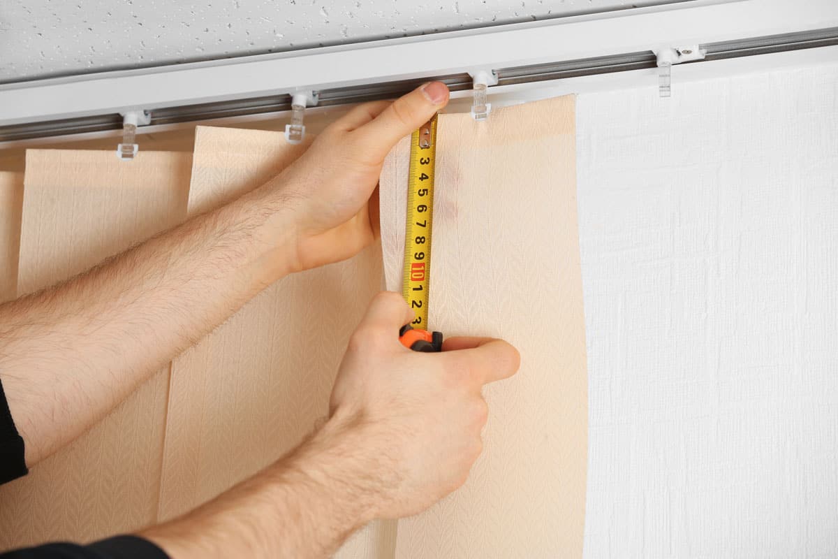 close up photo of a man installer measuring the vertical blinds
