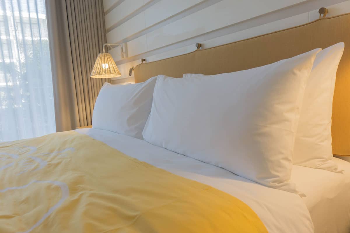 full king size bed yellow bedspread, white curtain white pillow case
