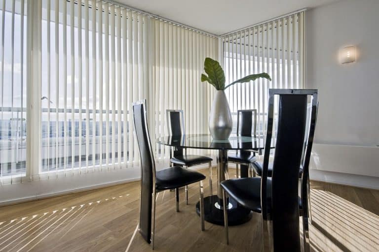 stylish modern dining room with a round glass top table and seats for five, Should Vertical Blinds Touch The Floor?