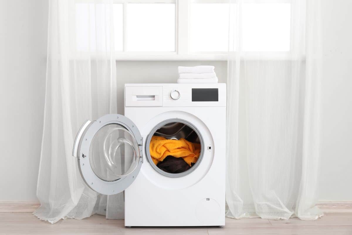 Modern washing machine with laundry near window